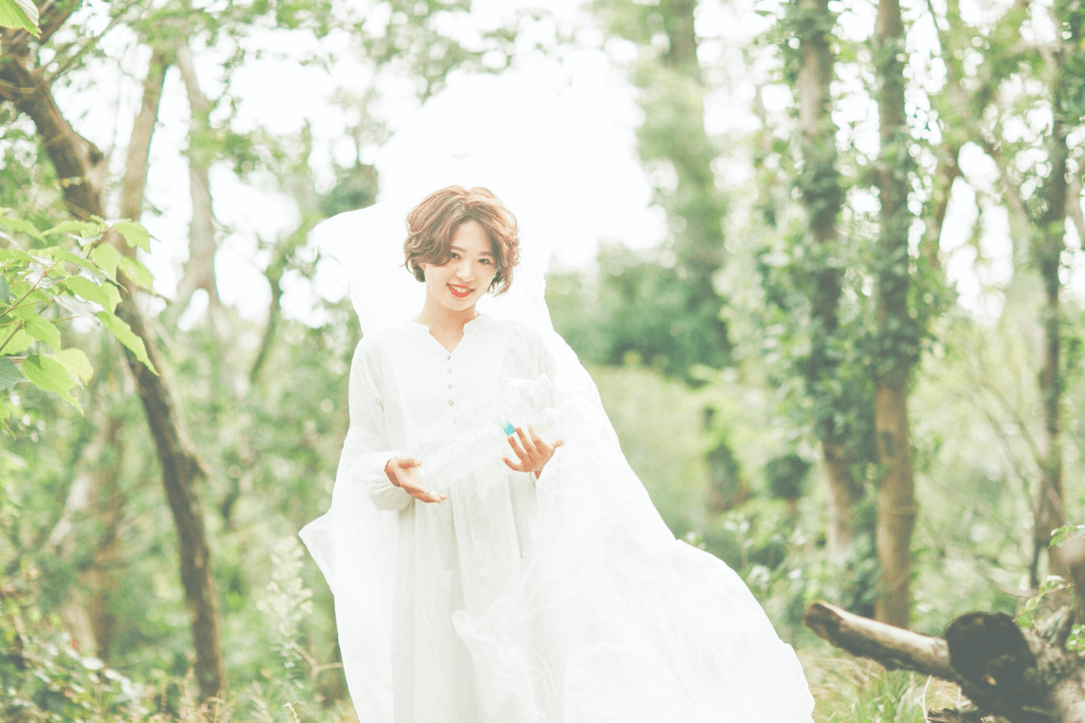 女性が草原で両腕を空に広げている画像